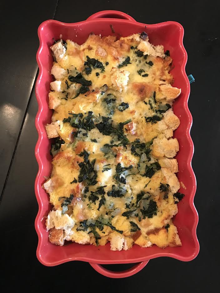 a casserole dish filled with spinach and cheese strata