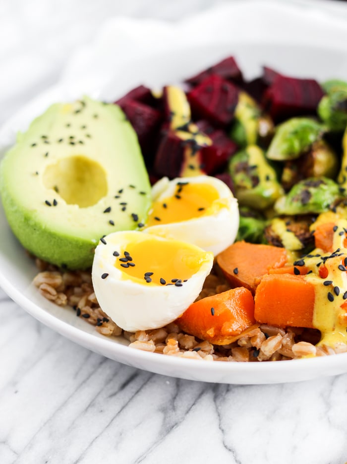 A buddha bowl topped with avocado, hard-boiled eggs, and beets